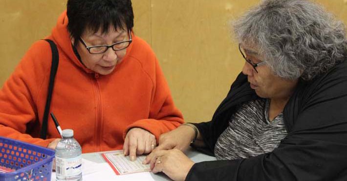 Two women work together, pointing at a paper on a table.