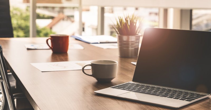 A laptop on a table with a mug and some papers