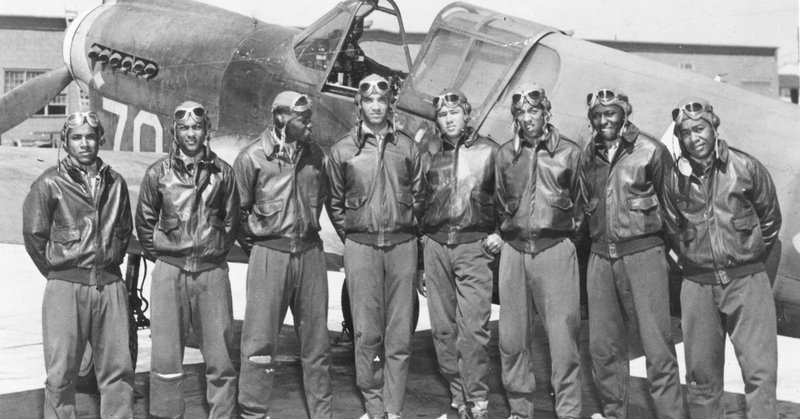 Eight men in jackets and aviation goggles in front of aircraft