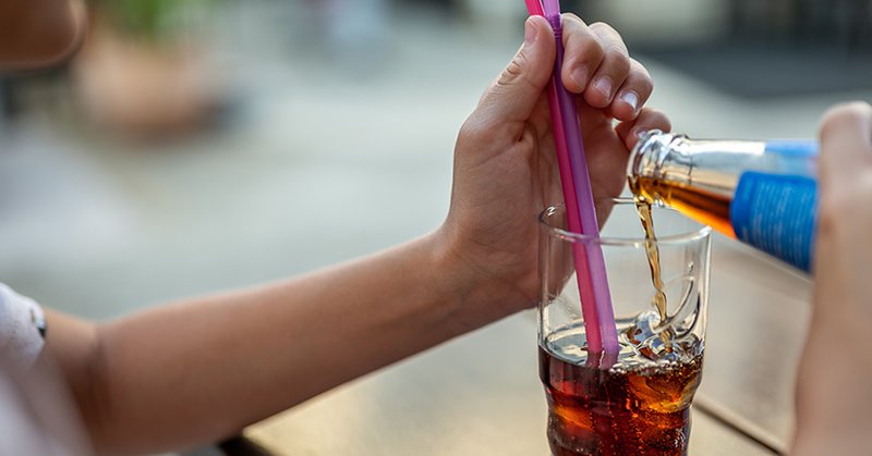 Child's hands pouring a drink into a glass