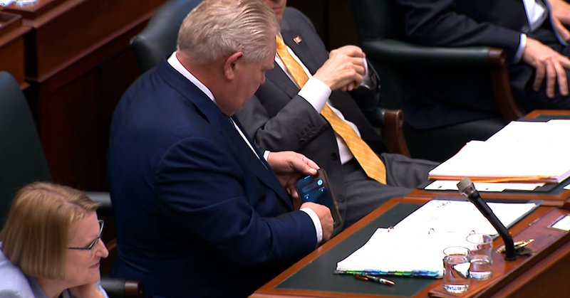 Ontario Premier Doug Ford check in cell phone phile in the legislature.