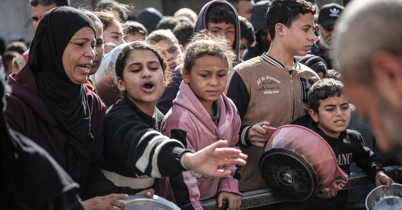 KHAN YUNIS, GAZA - DECEMBER 30: Palestinians, including children, who are struggling to access food gather to receive hot meals distributed by a charity organization in Khan Yunis, Gaza on December 30, 2025. The food crisis in Gaza continues as Israel allows only a limited amount of humanitarian aid to enter the city. (Photo by Abed Rahim Khatib/Anadolu via Getty Images)