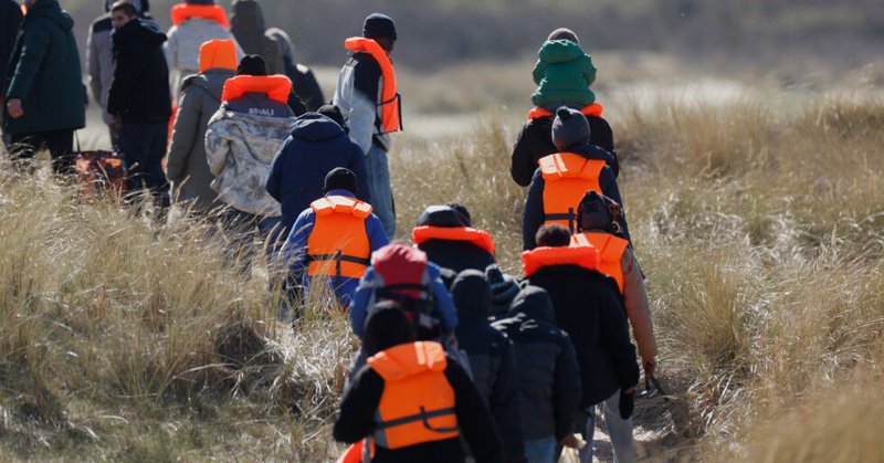 Migrants trying to reach Britain, walk on a beach shore in Gravelines, northern France, Wednesday, March 18, 2026. (AP Photo/Jean-Francois Badias)