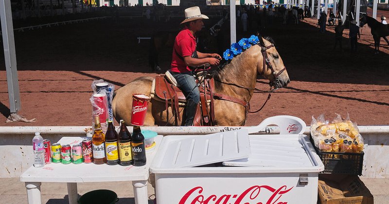 A rider trots past a refreshment stand at a horse festival.