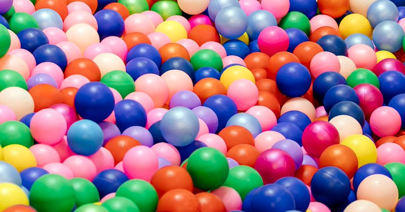 Colorful ball pit balls spanning the frame in a random arrangement.