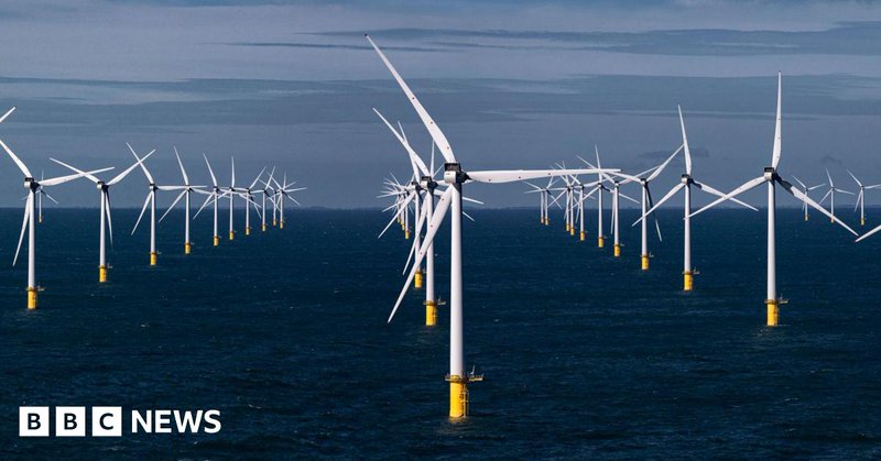 Offshore wind farm with several wind turbines standing in the ocean under a blue sky