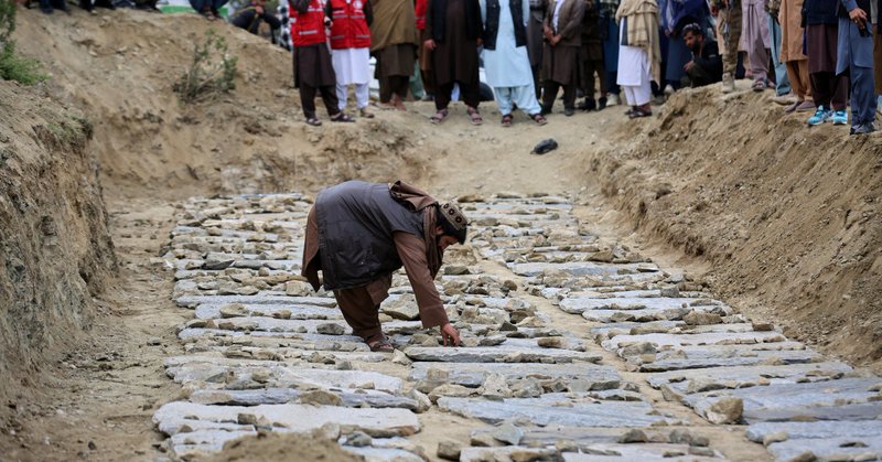 A man places stones on graves during a mass funeral for victims of the Pakistani airstrike on the Omid drug rehabilitation center in Kabul, Afghanistan