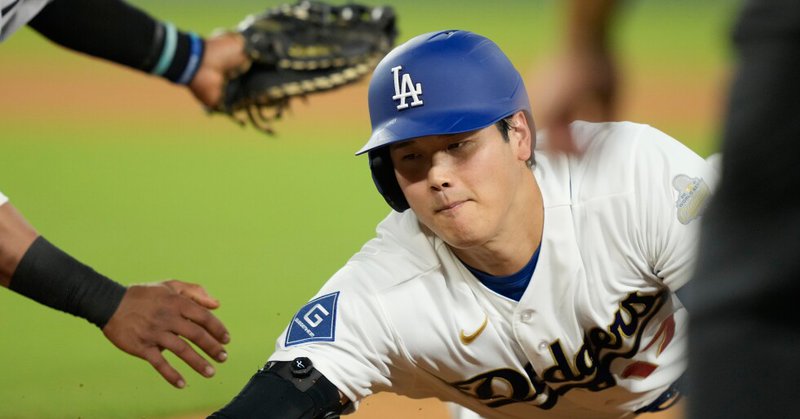 Los Angeles Dodgers designated hitter Shohei Ohtani slides safely into first base after a pickoff attempt against the Arizona Diamondbacks during the seventh inning of an opening-day baseball game Thursday, March 26, 2026, in Los Angeles. (AP Photo/Mark J. Terrill)