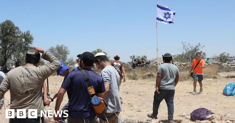 A group of Israeli settlers standing around or near an Israeli flag in the occupied West Bank (file photo)