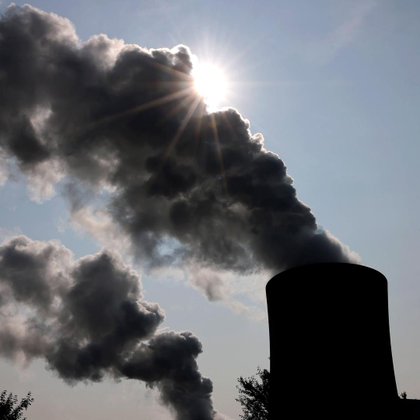 Das RWE-Kohlekraftwerk Neurath an einem sonnigen Vormittag. Die Sonne verschwindet hinter Emissionen aus den Kraftwerkstürmen.
