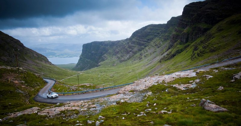 An image collage containing 1 images, Image 1 shows A white convertible car drives on a winding road through the Scottish Highlands