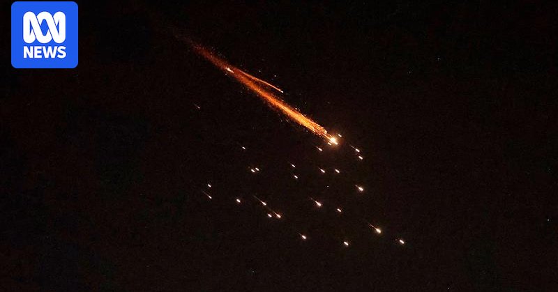 Orange rocket trails are seen in the night sky