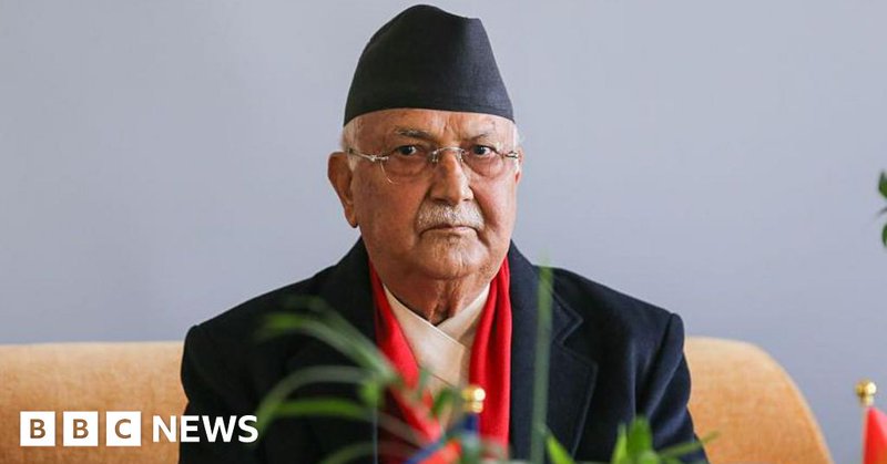 A man wearing a black suit and black hat looks at the camera
