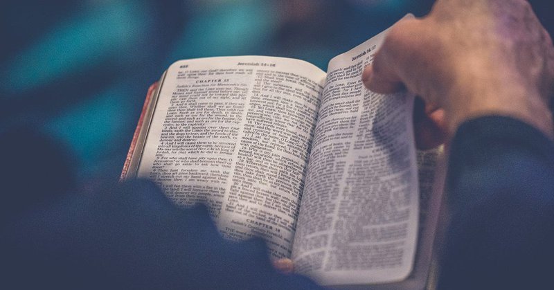 Picture of an open Bible with a hand turning a page
