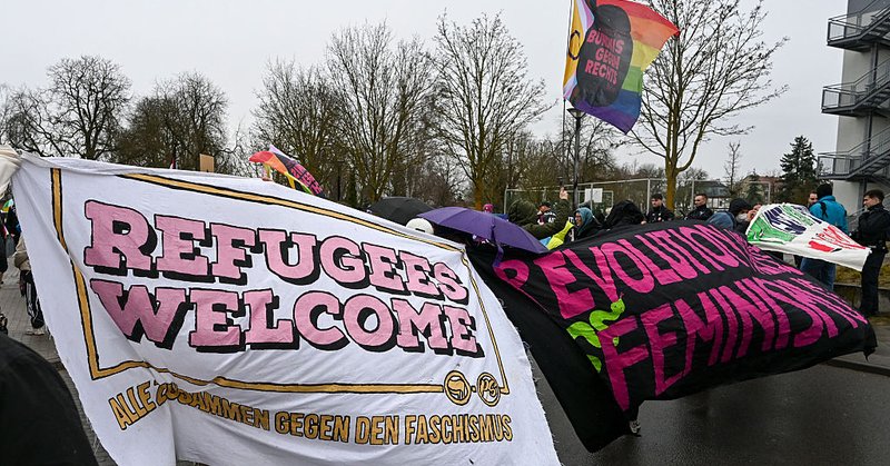 Counter demonstrators hold up a “refugees welcome” banner