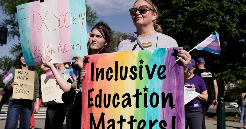 A woman is holding a sing that has the rainbow painted on it with words that read "Inclusive Education Matters!"