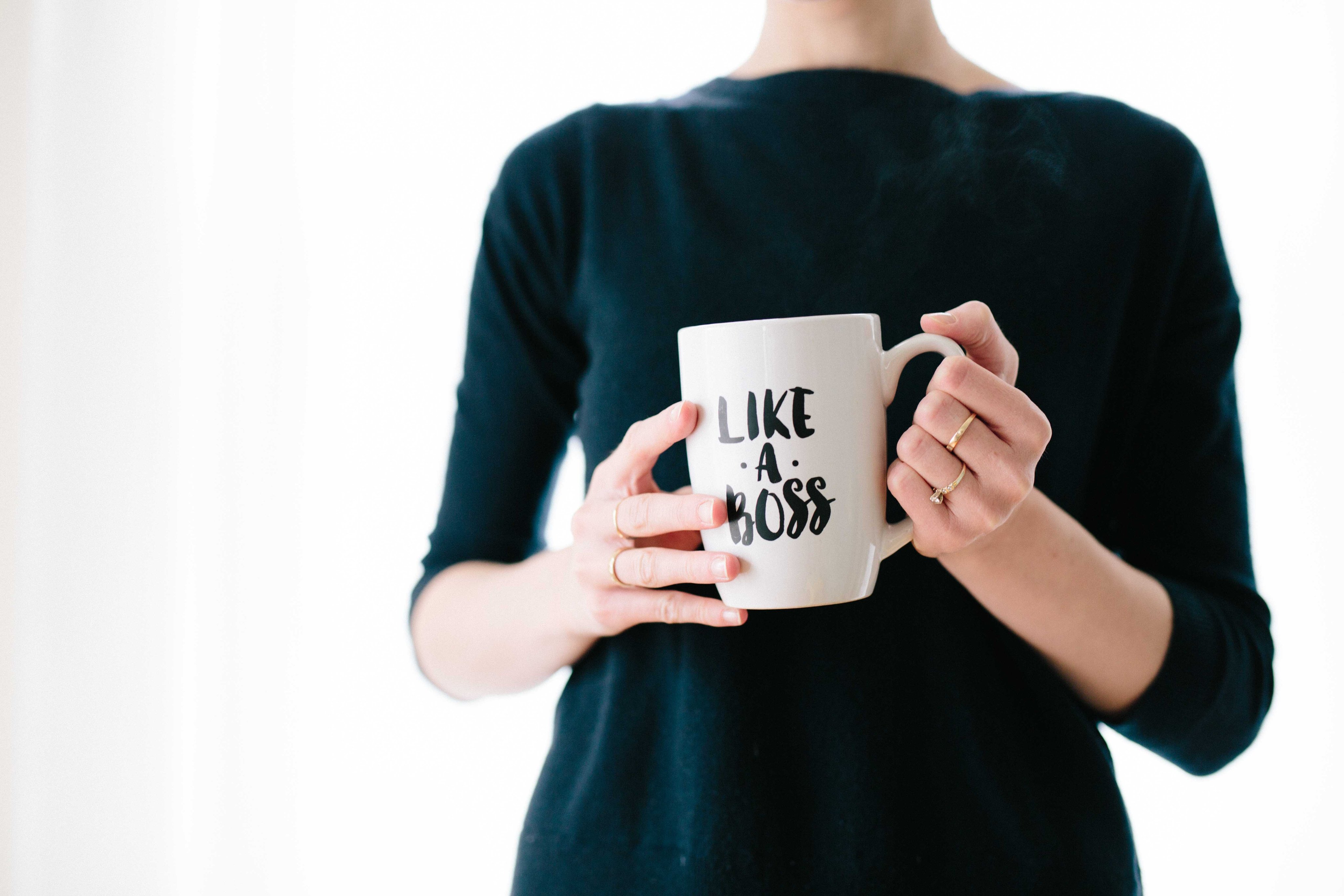 Person in a navy dress holding a large mug that says 'LIKE A BOSS'.