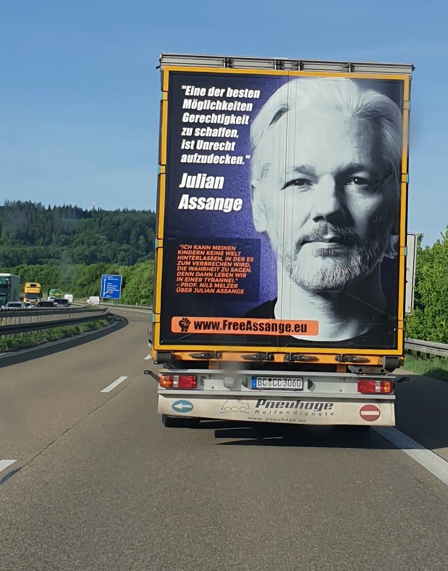 LKW mit großem Foto von Julian Assange und dem Zitat: "Eine der besten Möglichkeiten Gerechtigkeit zu schaffen, ist Unrecht aufzudecken" auf der A7