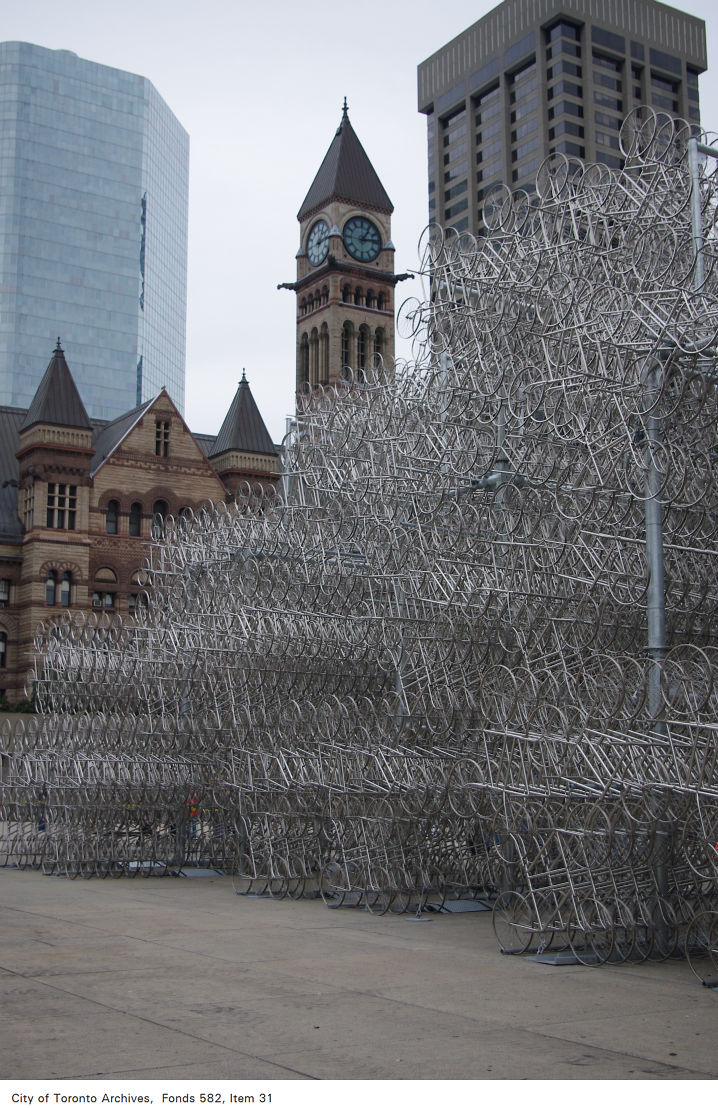 A colourr photograph of Ai Weiwei's sculpture 'Forever Bicycles'. This large sculpture of hundreds of silver bicycles stands in front of City Hall. 
