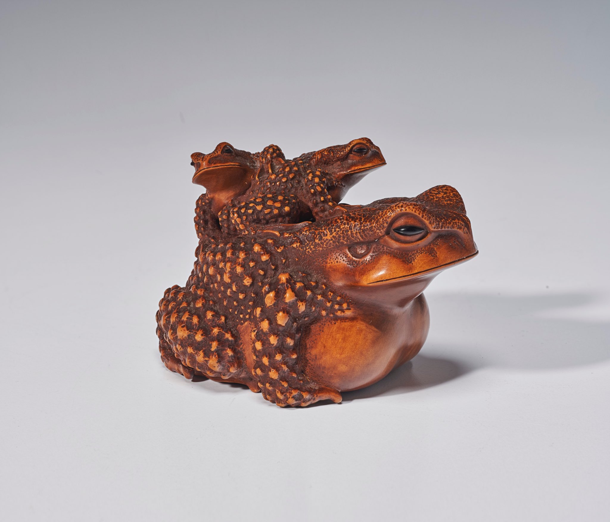 official auction photo #1, quarter turn side profile facing right on grey background
“Finely carved as two small toads on top of a large toad, the surface finished to resemble the toad's rugged skin, signature on underside.”