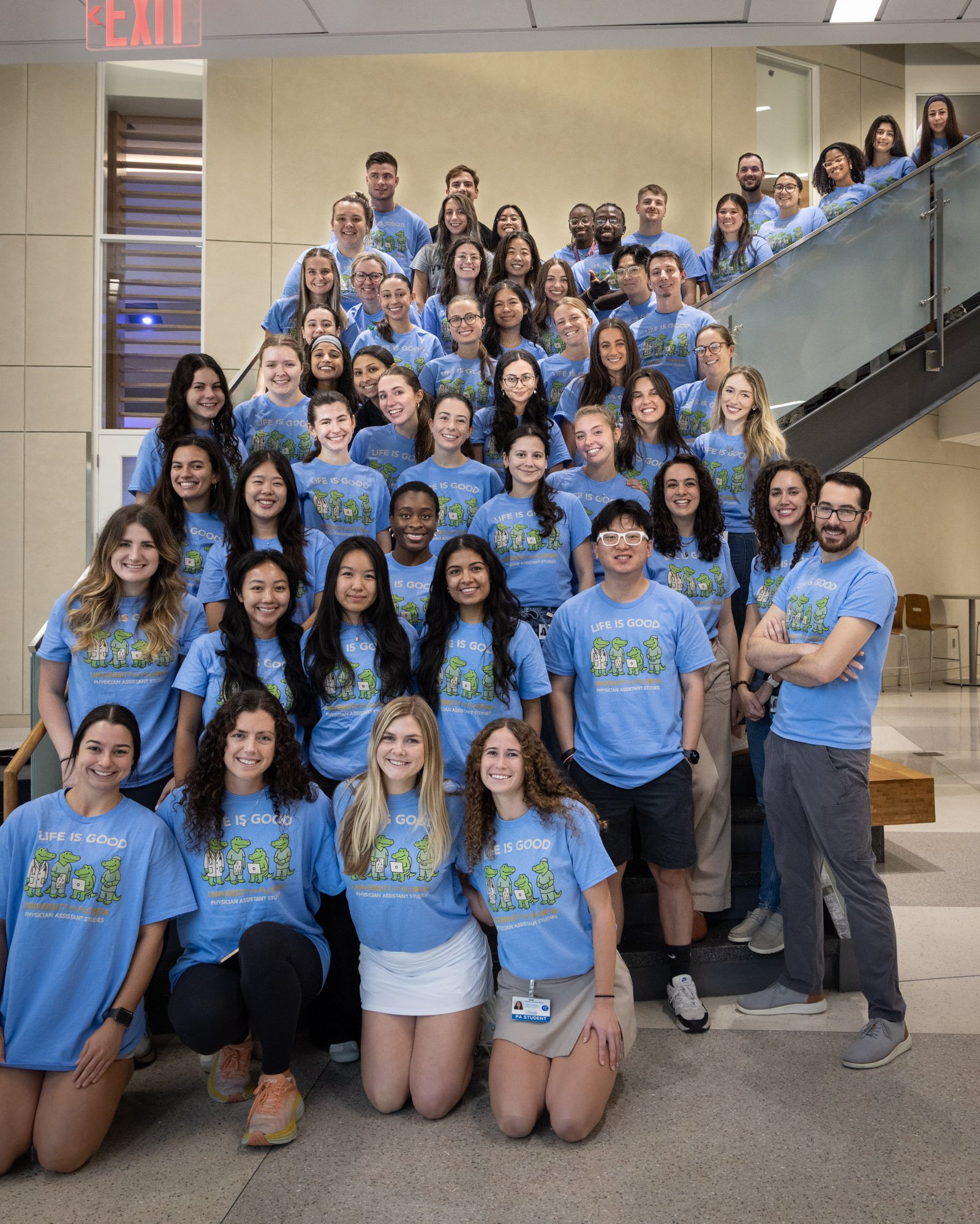 A class photo of UF PA students wearing matching blue shirts.