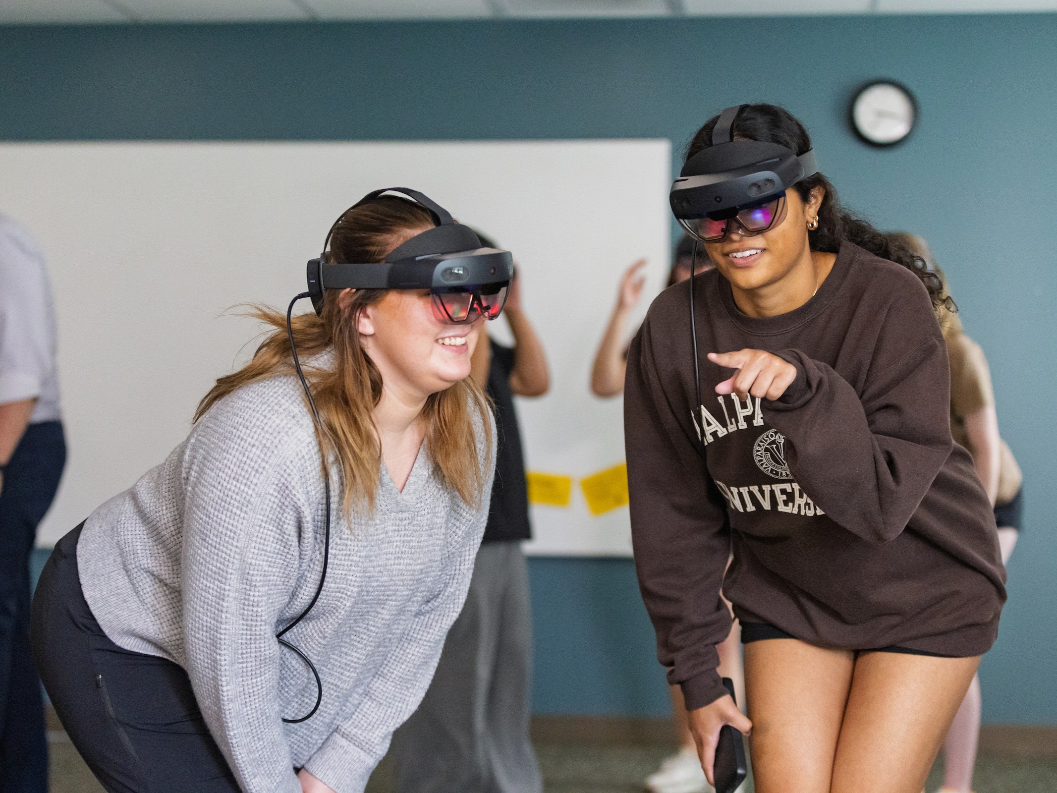 Two Valparaiso University master of science in physician assistant studies students smile as they interact with virtual reality equipment.