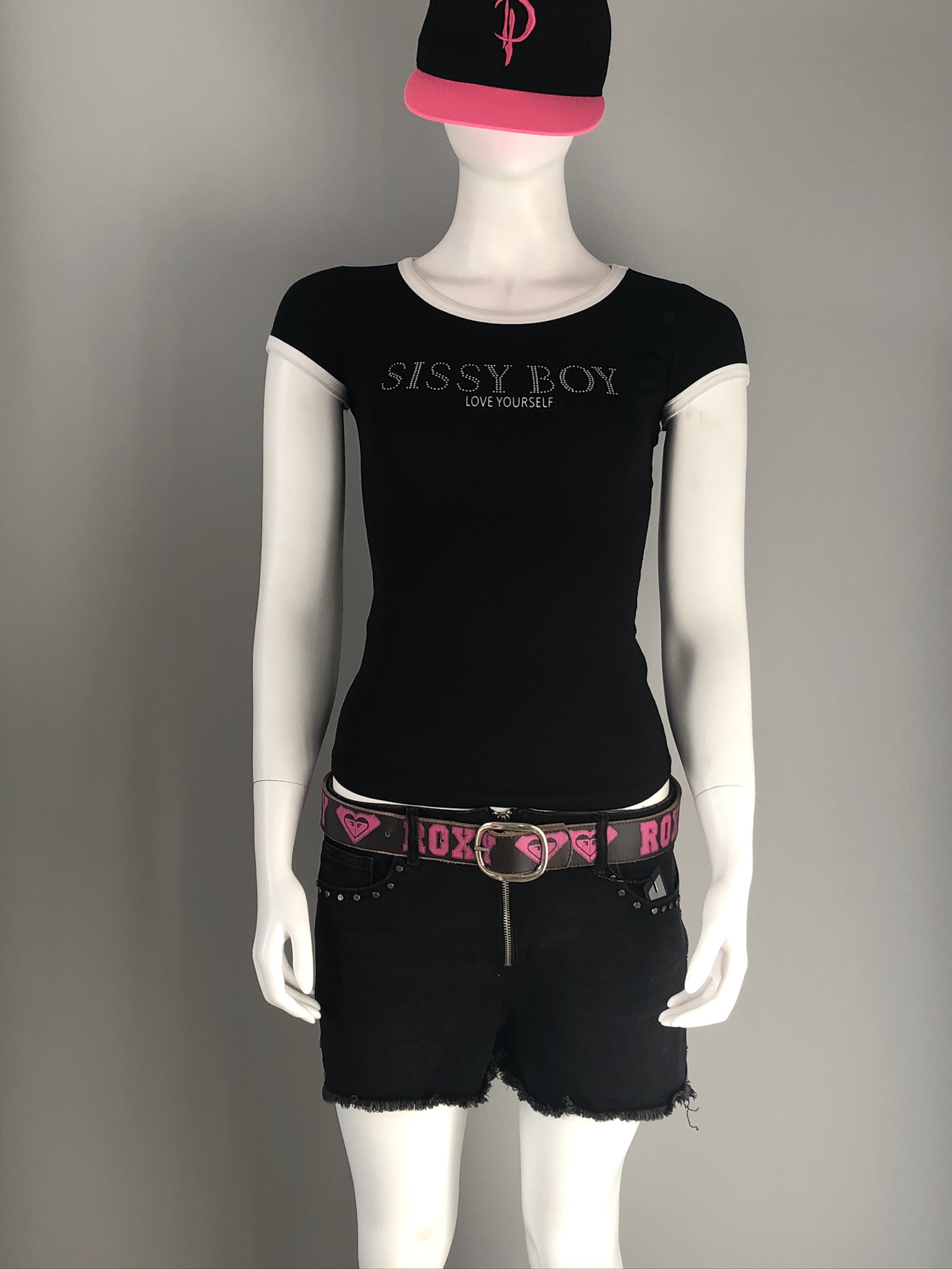 Displayed on a mannequin - Sissy Boy Love Yourself T-Shirt in black with white trim on neck with sleeves with “Sissy Boy Love Yourself” slogan across the chest in metallic silver-tone studs.  
https://www.theshoppingcart.co.za/product-page/sissy-boy-love-yourself-t-shirt
Sissy Boy Raw Hem Denim Ryder Shorts in black with silver exposed zip and studs detail along the front pockets. Worn with Roxy belt - not for sale). https://www.theshoppingcart.co.za/product-page/sissy-boy-raw-hem-denim-shorts

