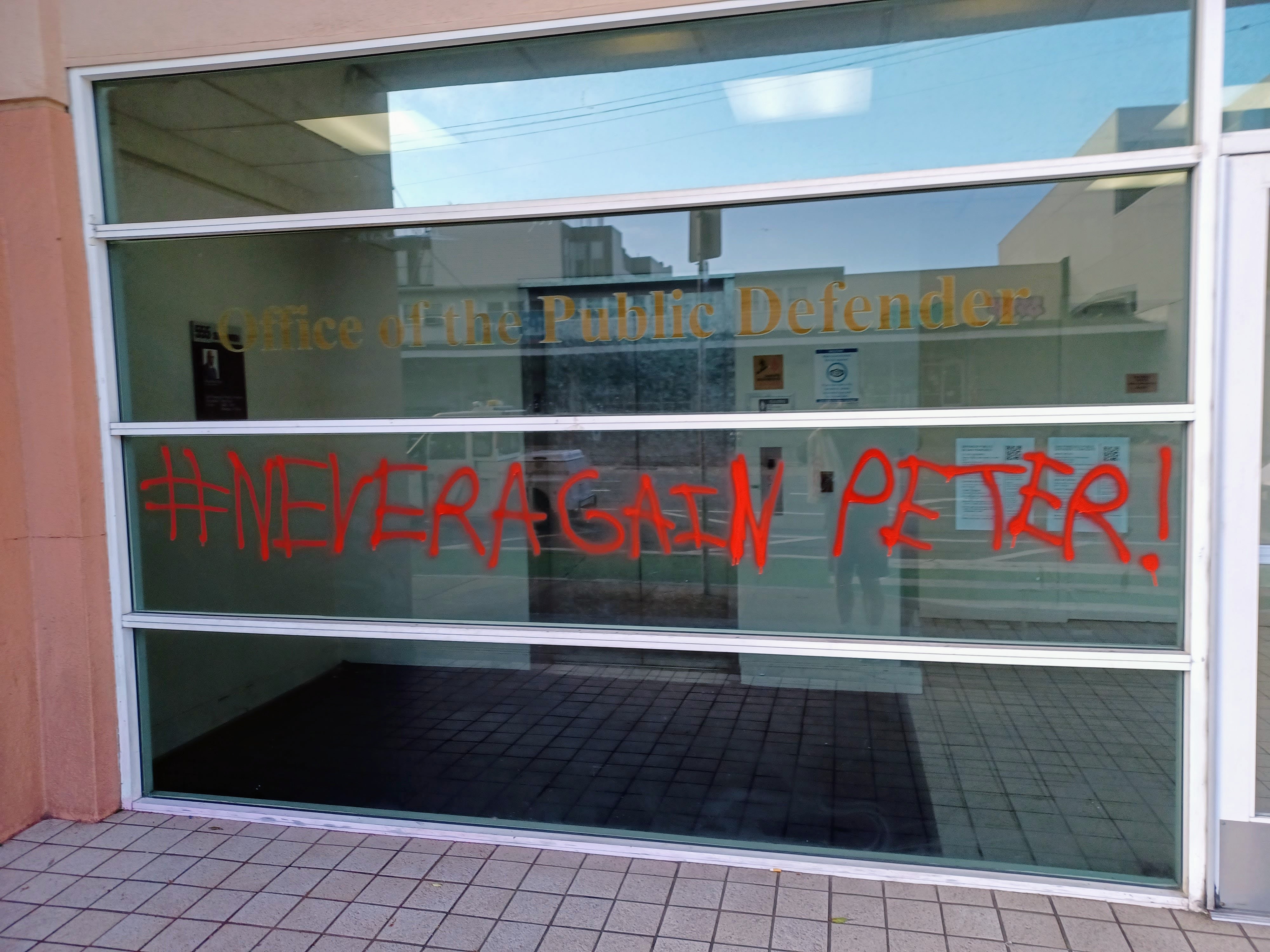 #NeverAgainPeter!" in red on Public Defender's window Circa 2021. copyright 2021 All Rights Reserved