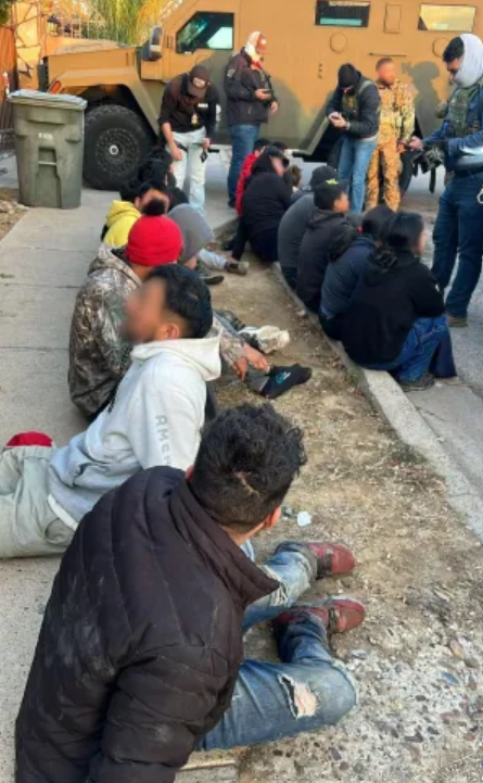 Apprehended suspects sitting on the ground.