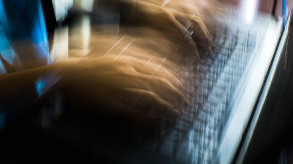 From above of crop anonymous person typing on keyboard of laptop in long exposure