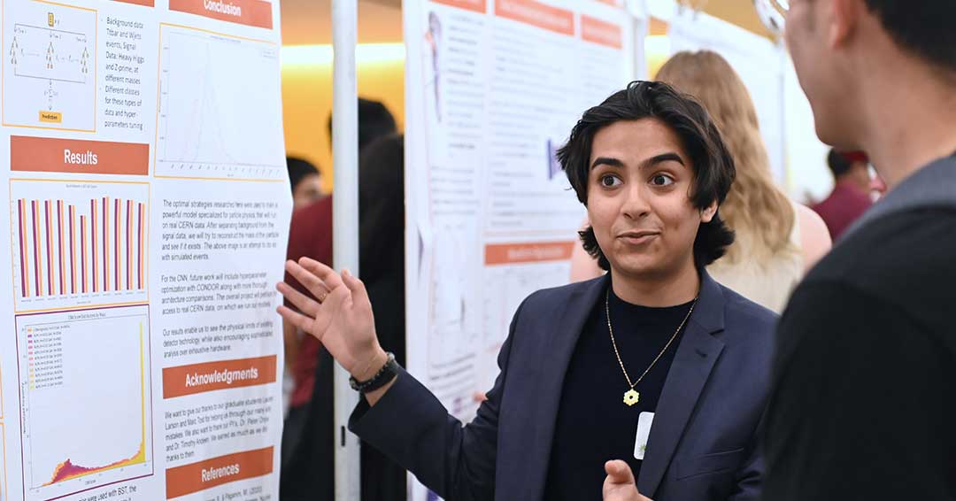 A young man explains their research to onlookers.