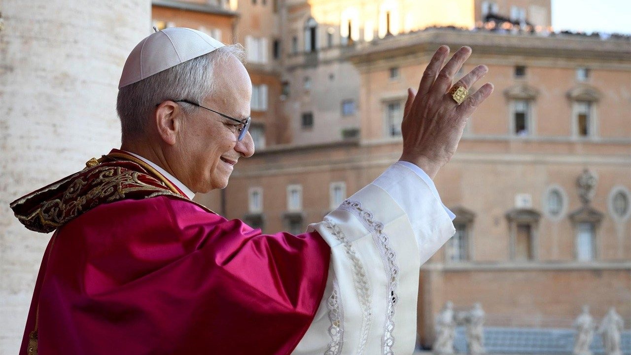 Foto del nou papa Lleó XIV tot saludant als assistents en la plaça del Vaticano, revestit com a Sant Pare, i somrient d'emoció.