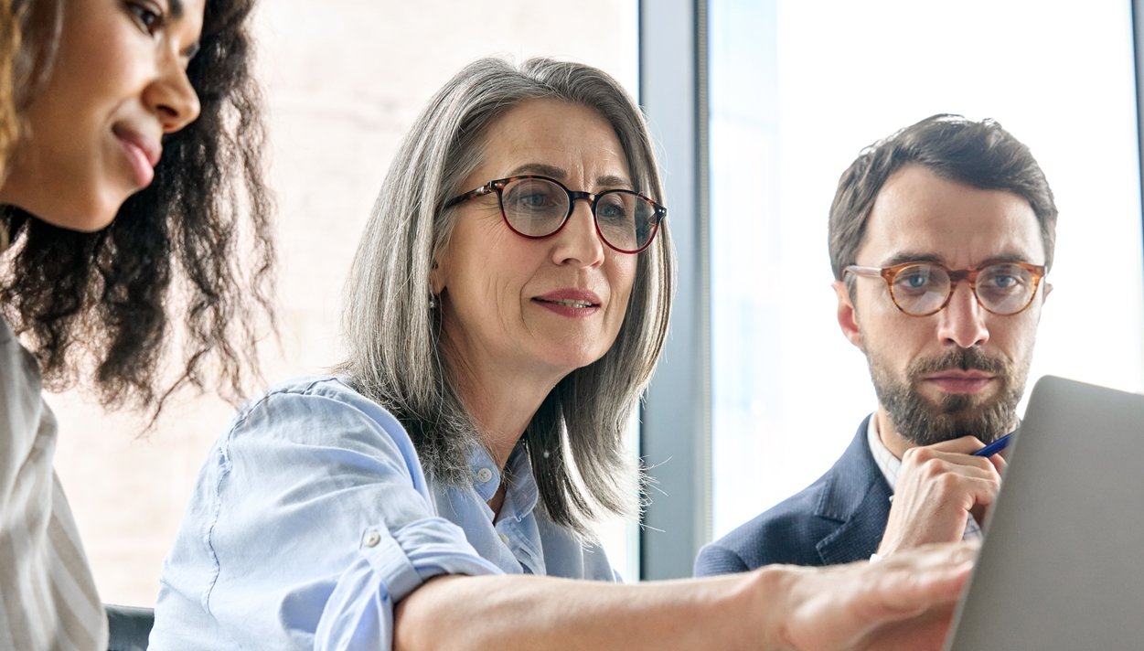 Group of three people of different ages working at a laptop
