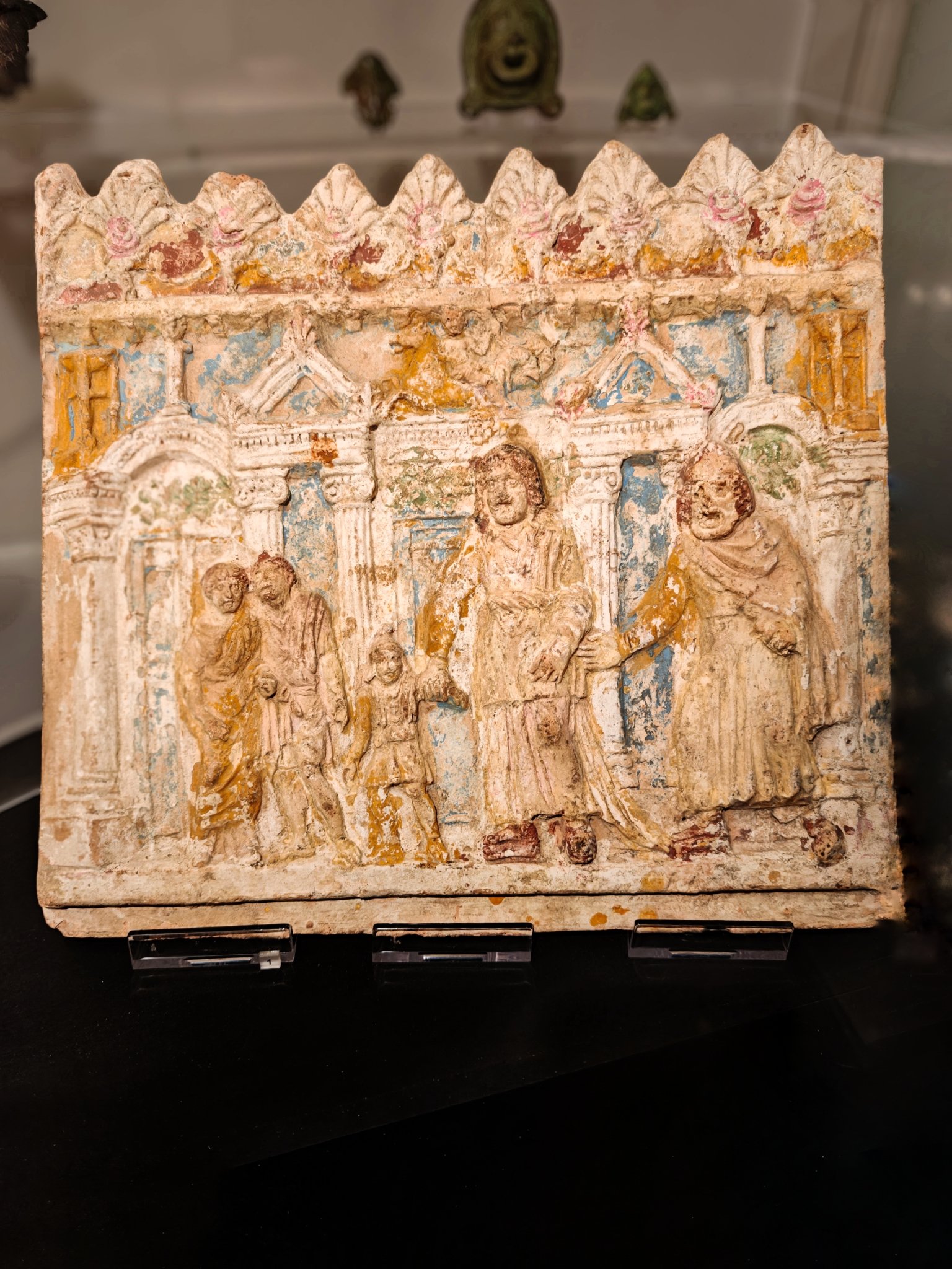 TERRACOTTA PLAQUE WITH TRAGIC SCENE, C. 20-10 BCE. PALAZZO MASSIMO ALLE TERME

This terracotta panel was found in the columbarium of P. Numitorius Hilareus along the via Salaria. It shows a play in progress against a backdrop of elaborate architecture. Two small figures at left are reacting like a chorus to the tragic events of a play by the late Republican author Accius based on the sack of Troy. Ulysses, the Latin form of Odysseus, stands at right, calling Astyanax, heir to the throne of Troy, to come to him. The boy, at centre left, is being held back by his mother Andromache. But his fate has been determined: either he will grow up to be a warrior who will devastate Achaia, or the Achaeans will kill him now. Ulysses throws him from the battlements of the burning city of Troy. 