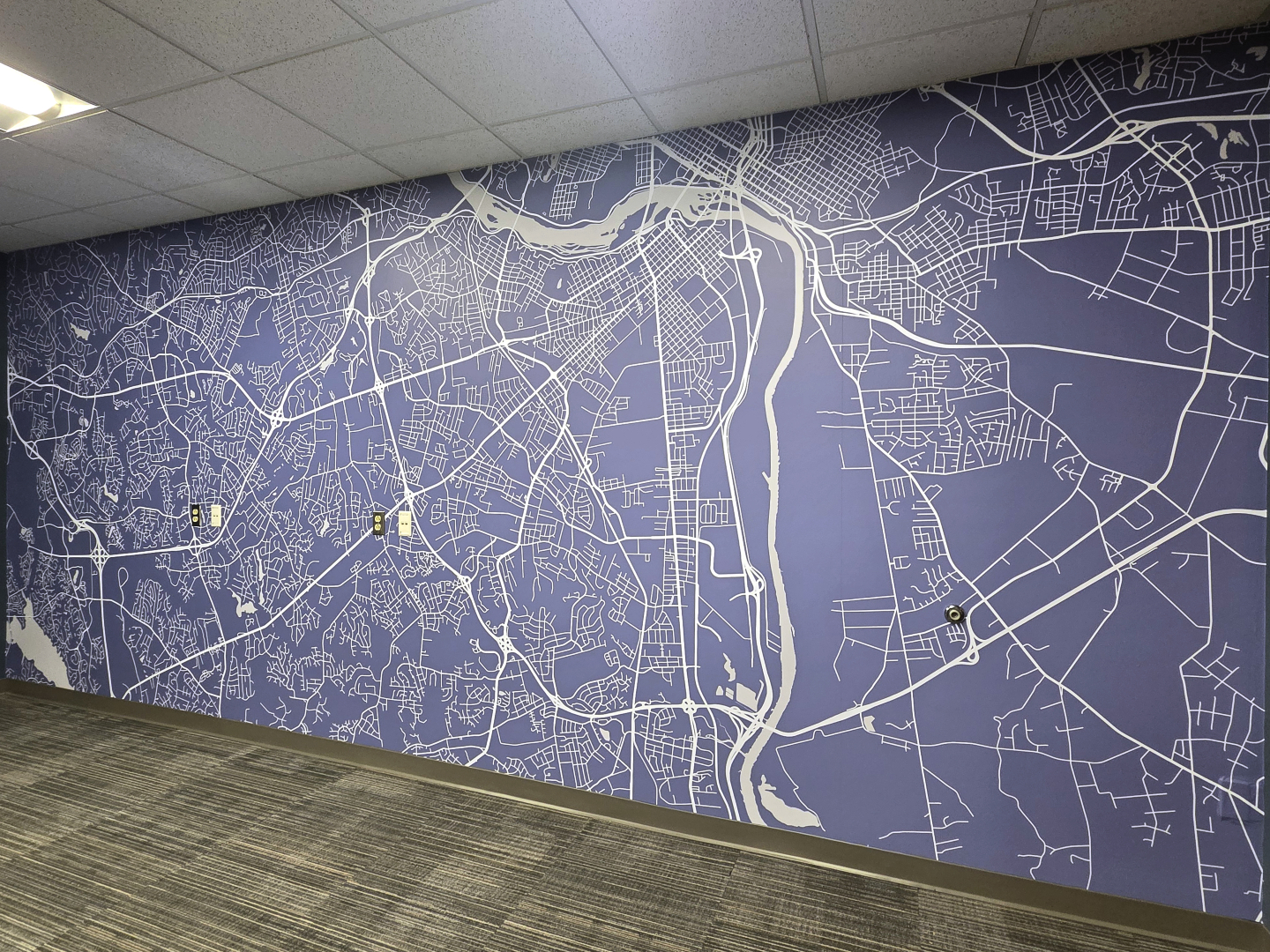 A wall mural depicting a detailed street map of a city, featuring various roads and a river running through the center.