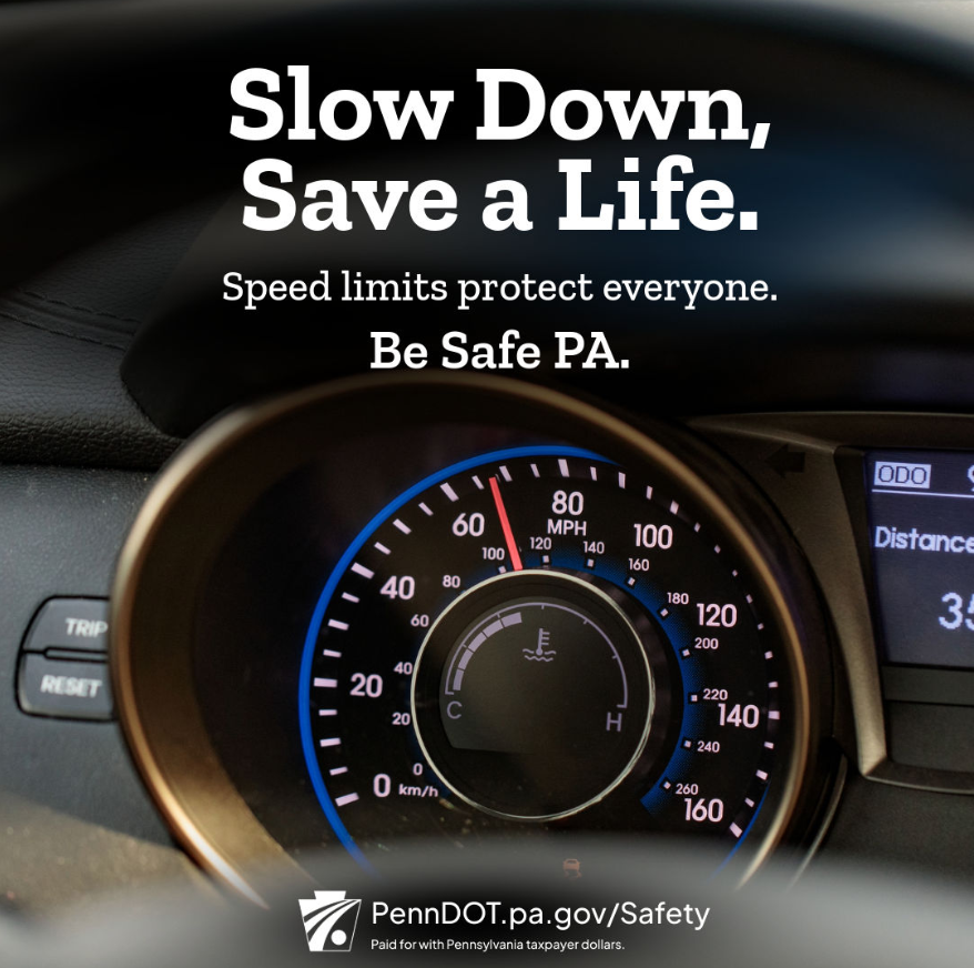 A close-up photo of a vehicle’s speedometer and dashboard with the needle pointing near 0 mph. Overlaid text reads: “Slow Down, Save a Life. Speed limits protect everyone. Be Safe PA.” At the bottom is the PennDOT logo and the web address PennDOT.pa.gov/Safety, along with a note stating it is paid for with Pennsylvania taxpayer dollars.