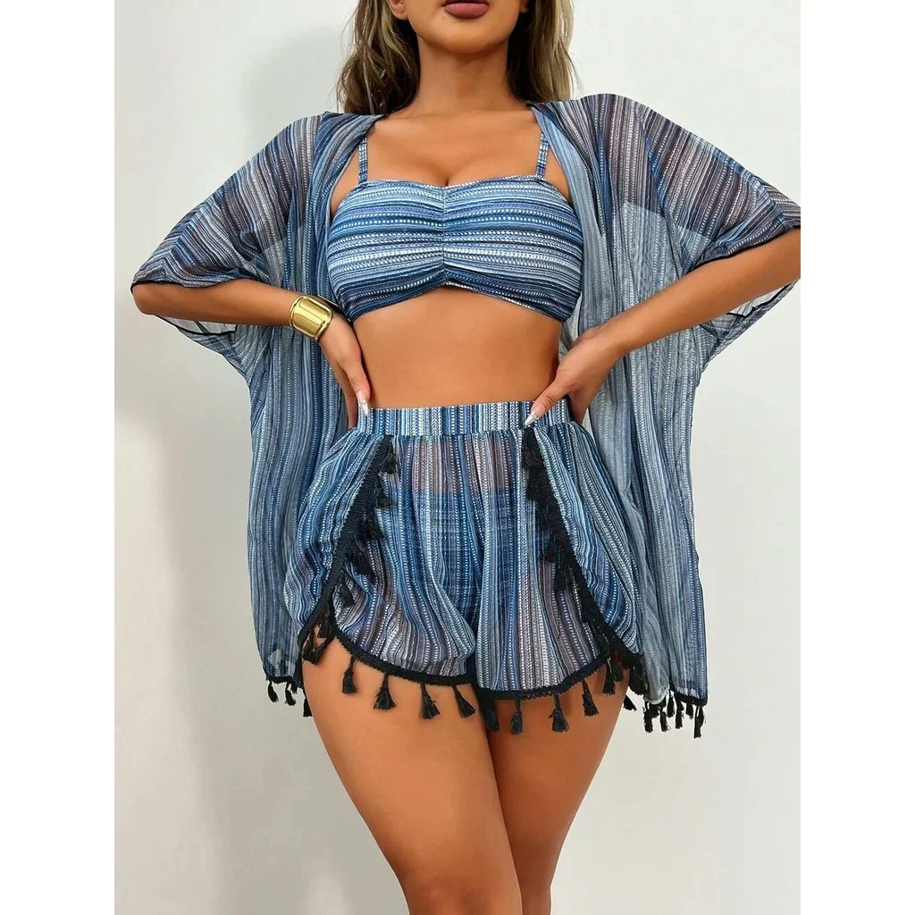 Imagem do conjunto feminino de quatro peças para praia e piscina, composto por um maiô com proteção solar UV, uma blusa com franjas decorativas, e peças de biquíni (top e calcinha) complementares. O conjunto está sobre um fundo de areia ou próximo à água, destacando o design moderno, as franjas, as cores vibrantes (como vermelho, preto ou azul) e o tecido com proteção UV.