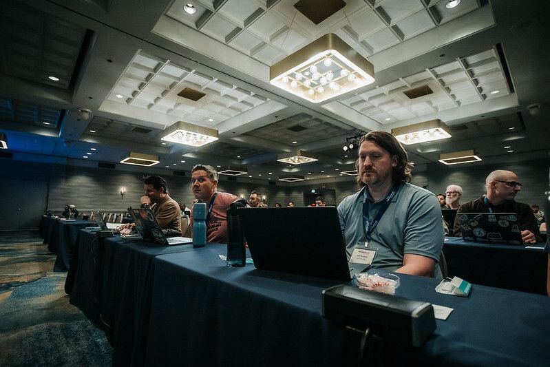 Jeff Triplett and Drew Winstel waiting for the next talk to start in the front row of DjangoCon US 2025