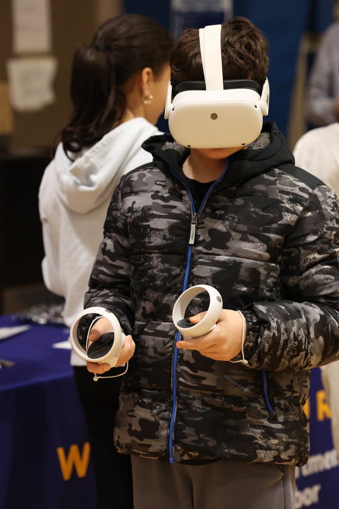 student tests out virtual reality head set and arm bands 