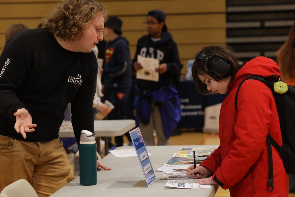 student talks to Hillside rep at EIMS Career Fair while writing on paper