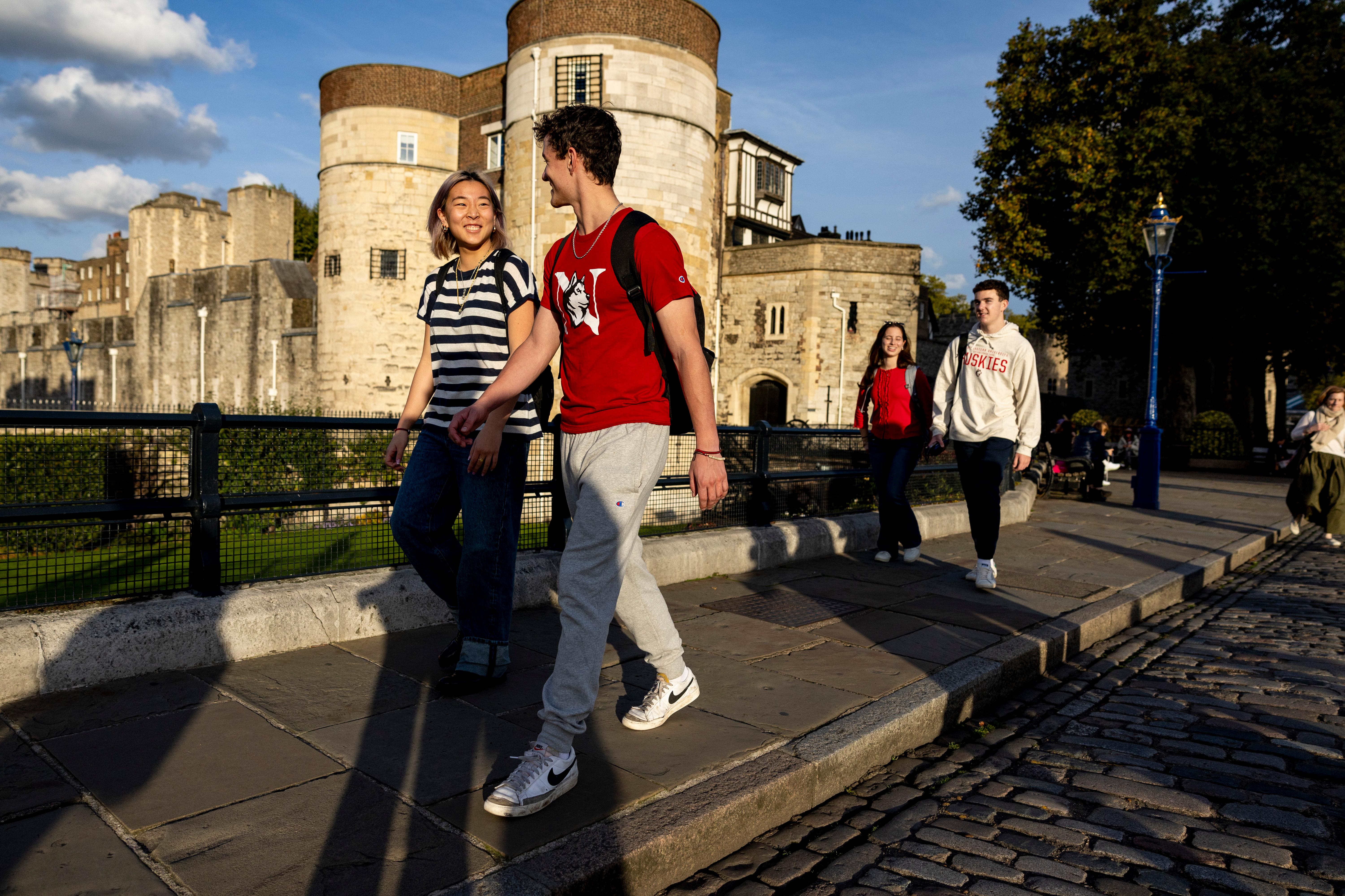 A group of students stroll past the Tower of London on a sunny spring day. 