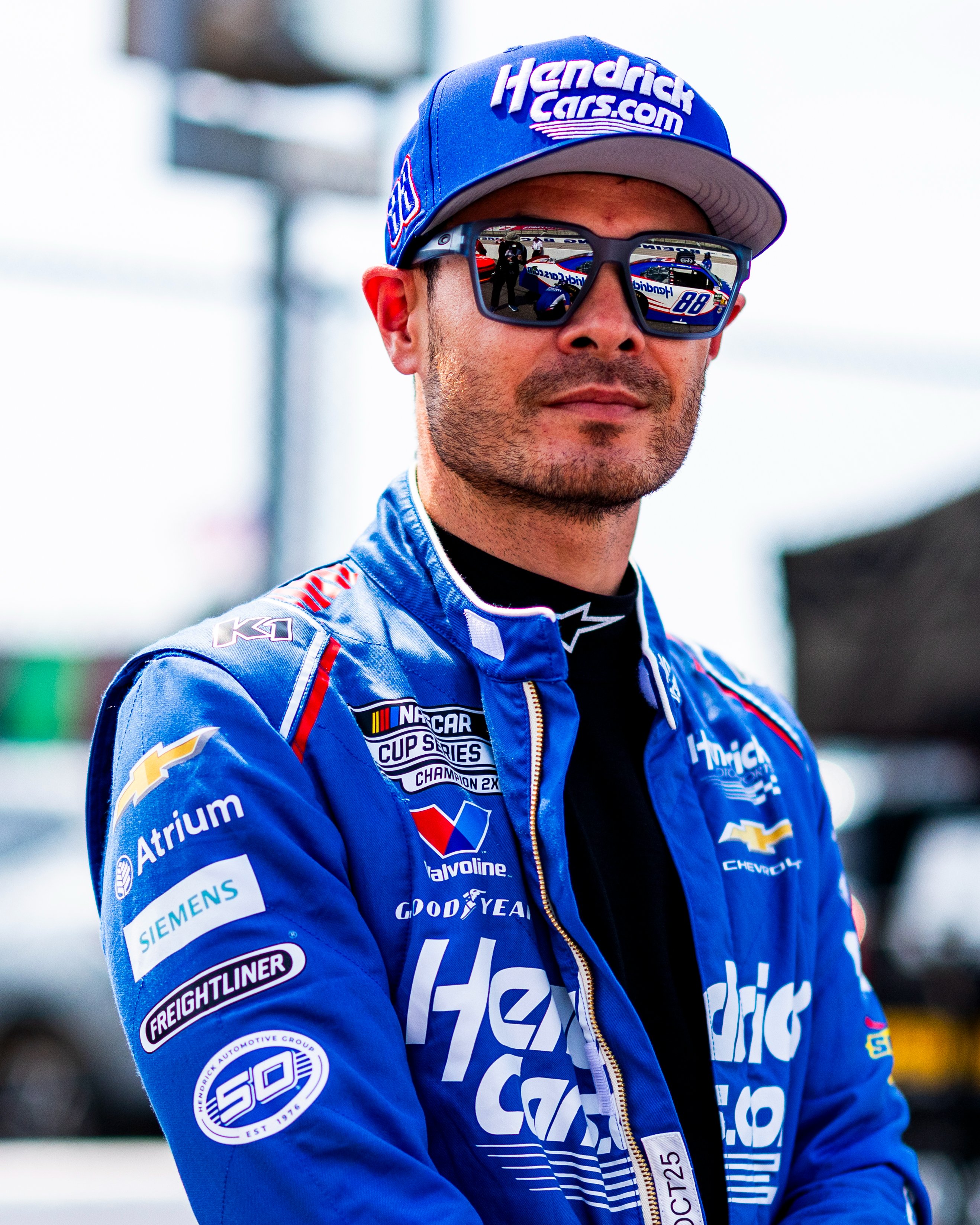 Kyle Larson on the grid at Darlington. His No. 88 car is reflected in his sunglasses.