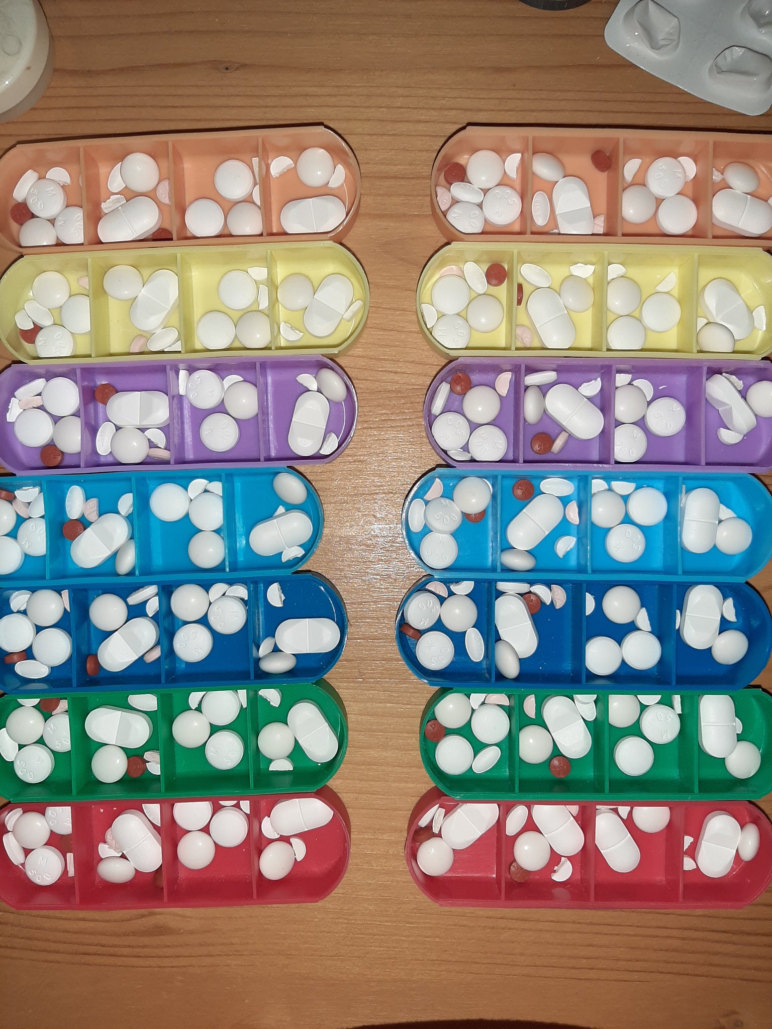 Verschiedenfarbige einzelne Dosetten aus der Medikamentenbox sind mit Medikamenten befüllt. Da ich nur morgens und abends Medikamente nehmen muss, habe ich die Dosetten mit 4 Fächern jeweils 2 für morgens und 2 für abends befüllt. So erreichen 2 Mediboxen für 4 Wochen.