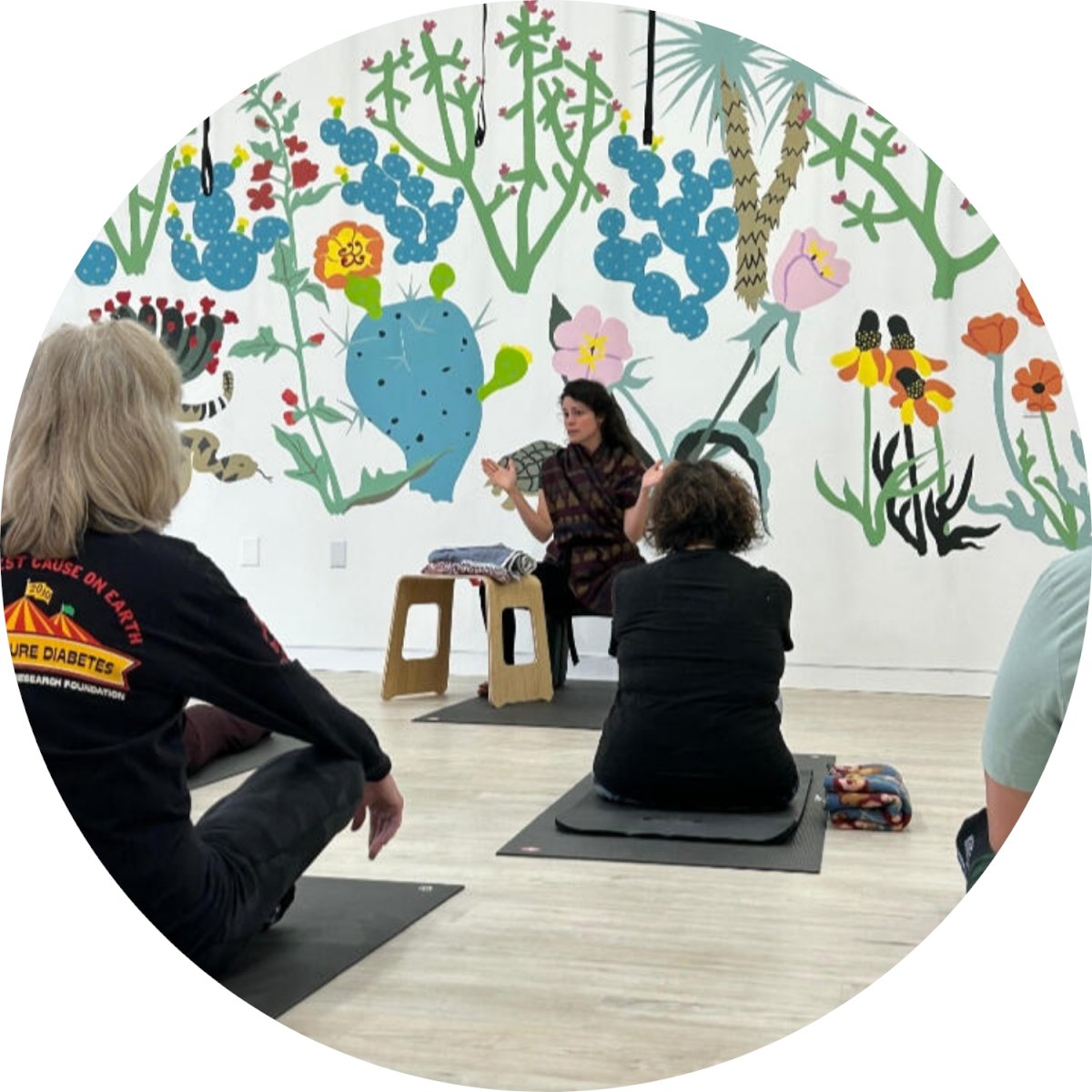 A group of people sitting on yoga mats listening to an instructor.