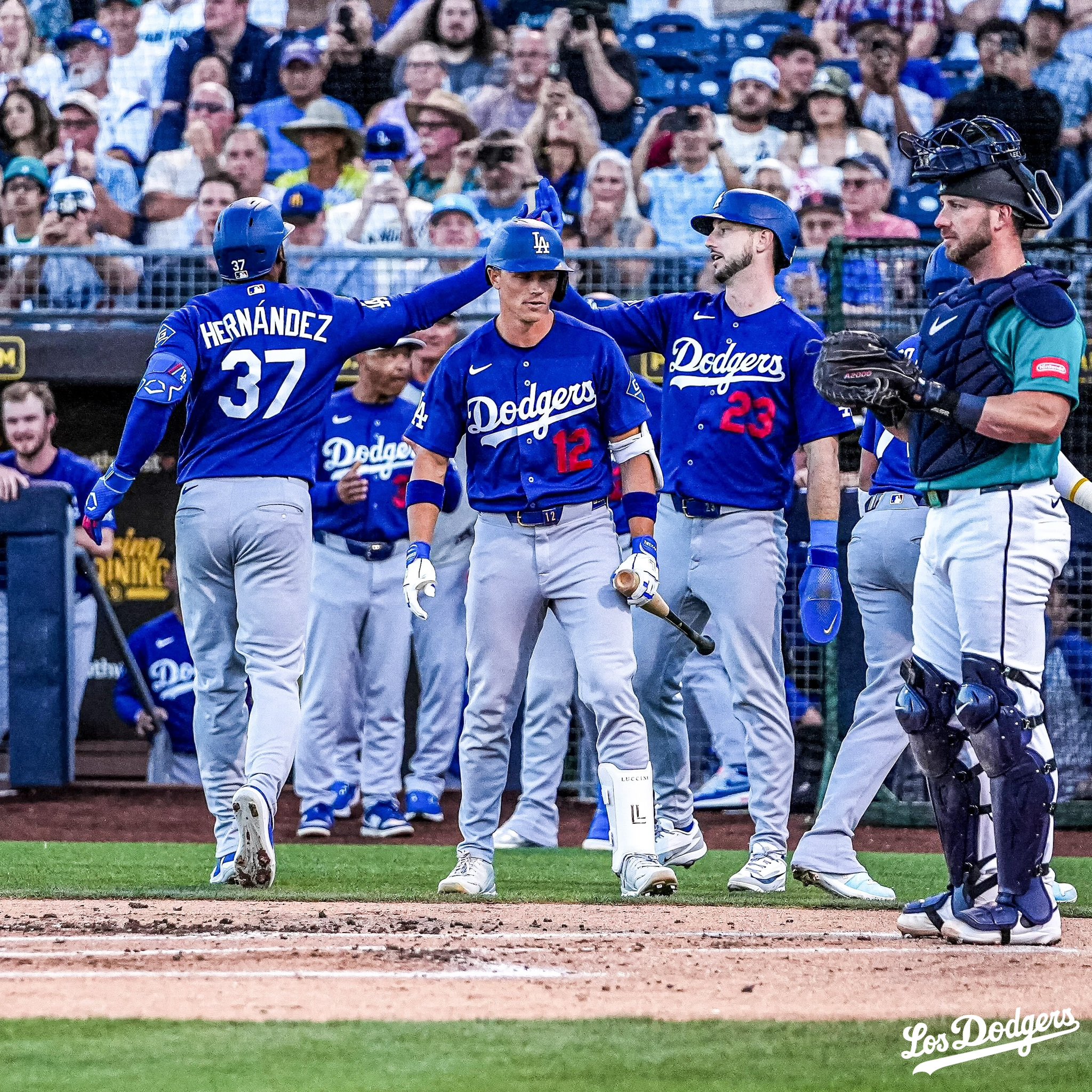 Teoscar Hernández es recibido en el plato por sus compañeros.