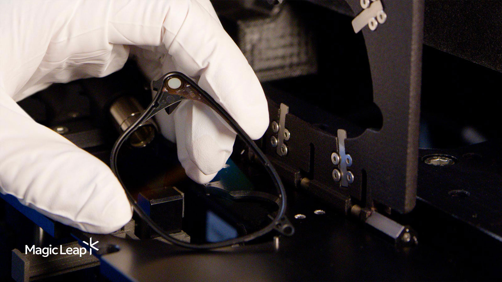 A Magic Leap technician holds a waveguide after it has been inserted into a polymer frame. 
