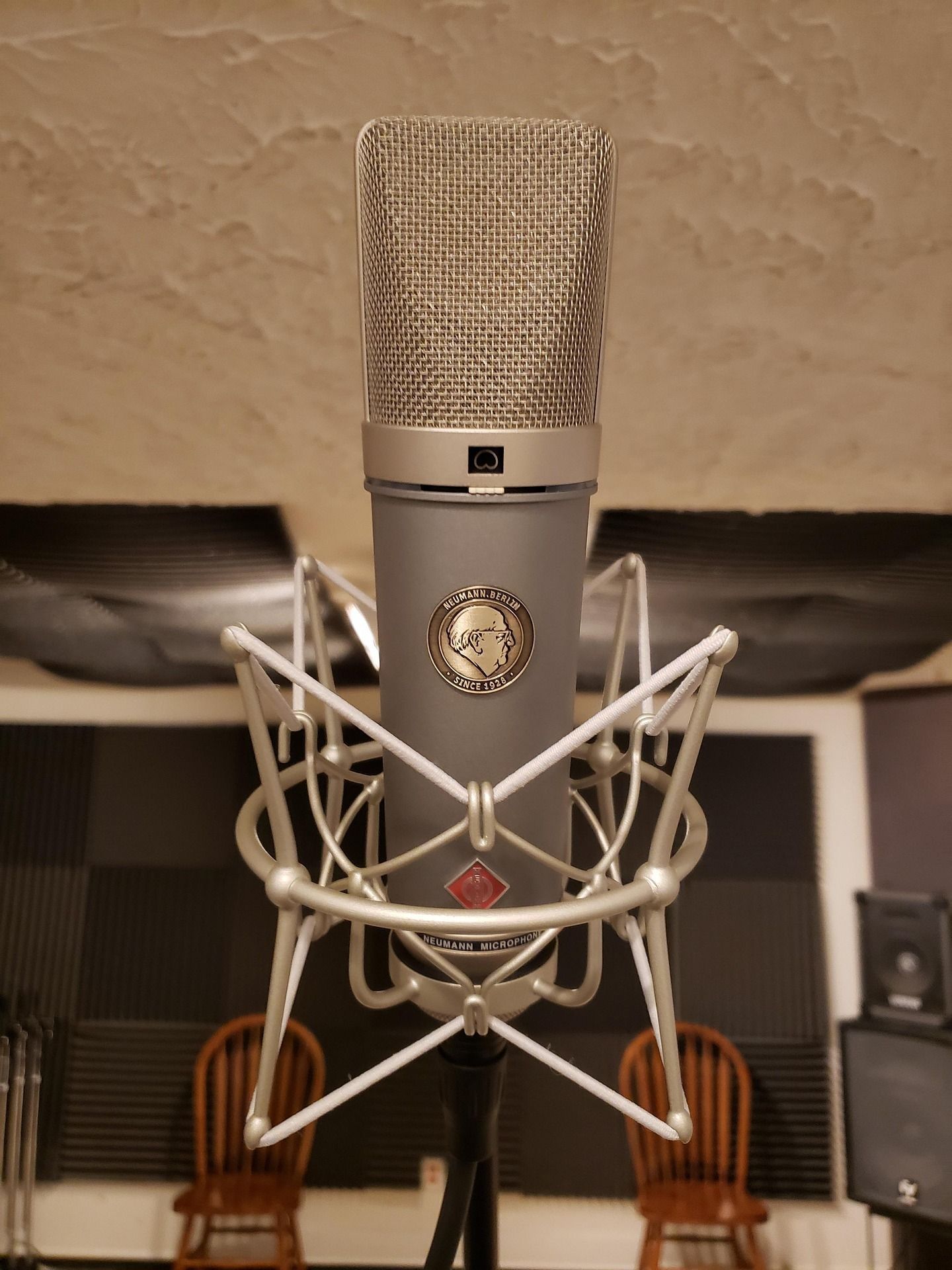 Neumman condensor microphone setup in a recording booth large enough for an entire band, perfectly padded for sound capture.