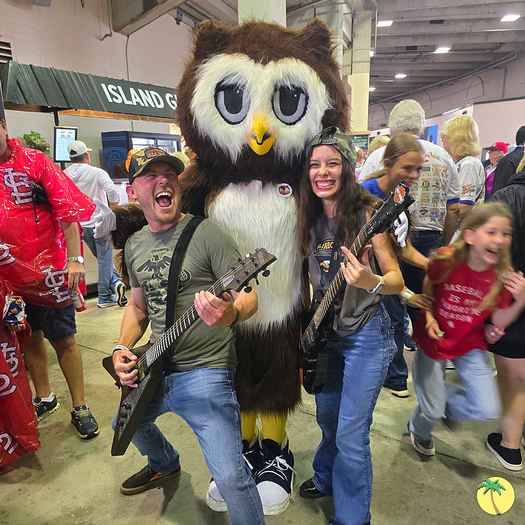 Dewey posing with two people holding electric guitars and smiling.