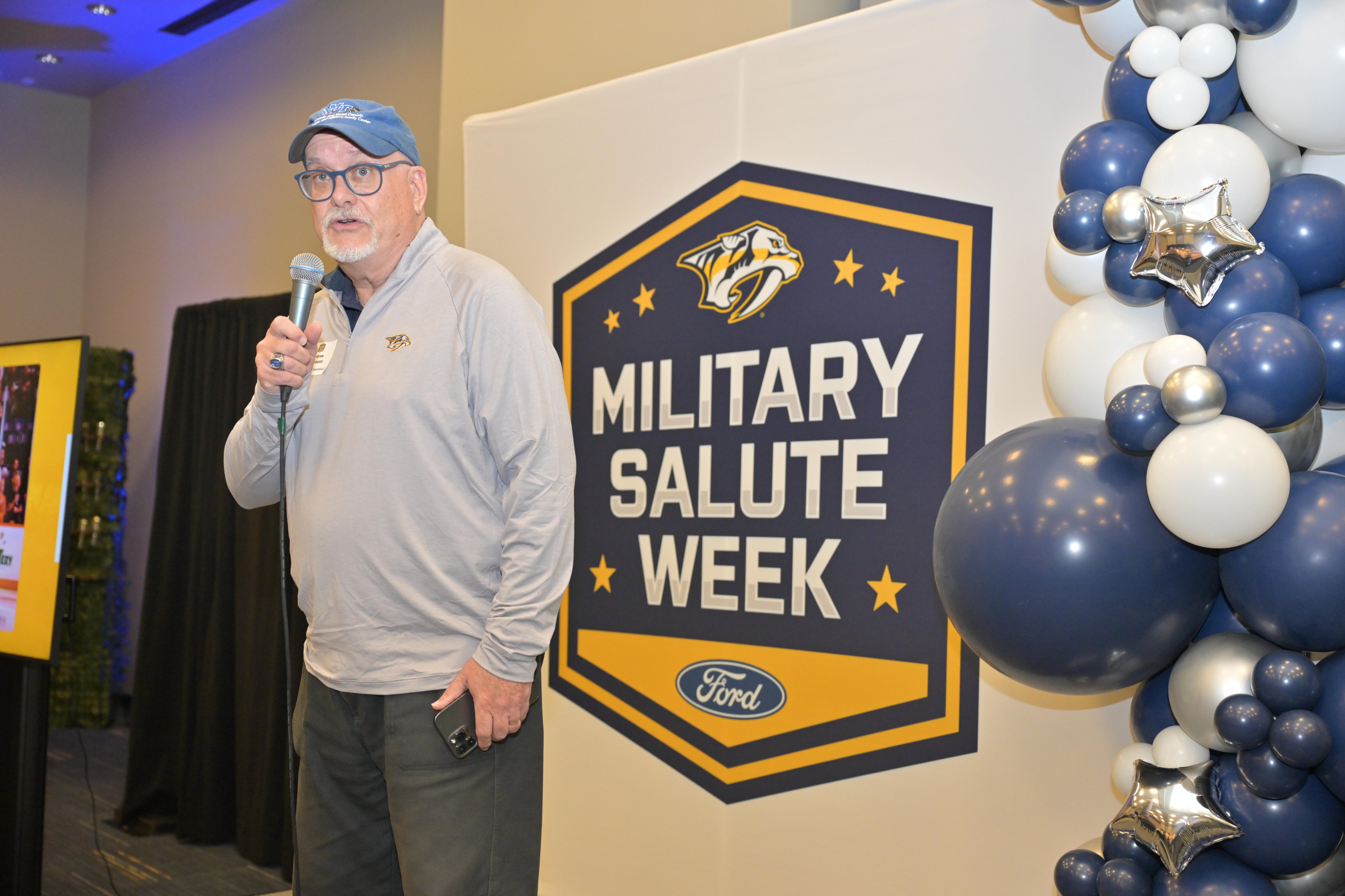 MTSU VP Andrew Oppmann holding a microphone at the Nashville Predators Military Salute Week event