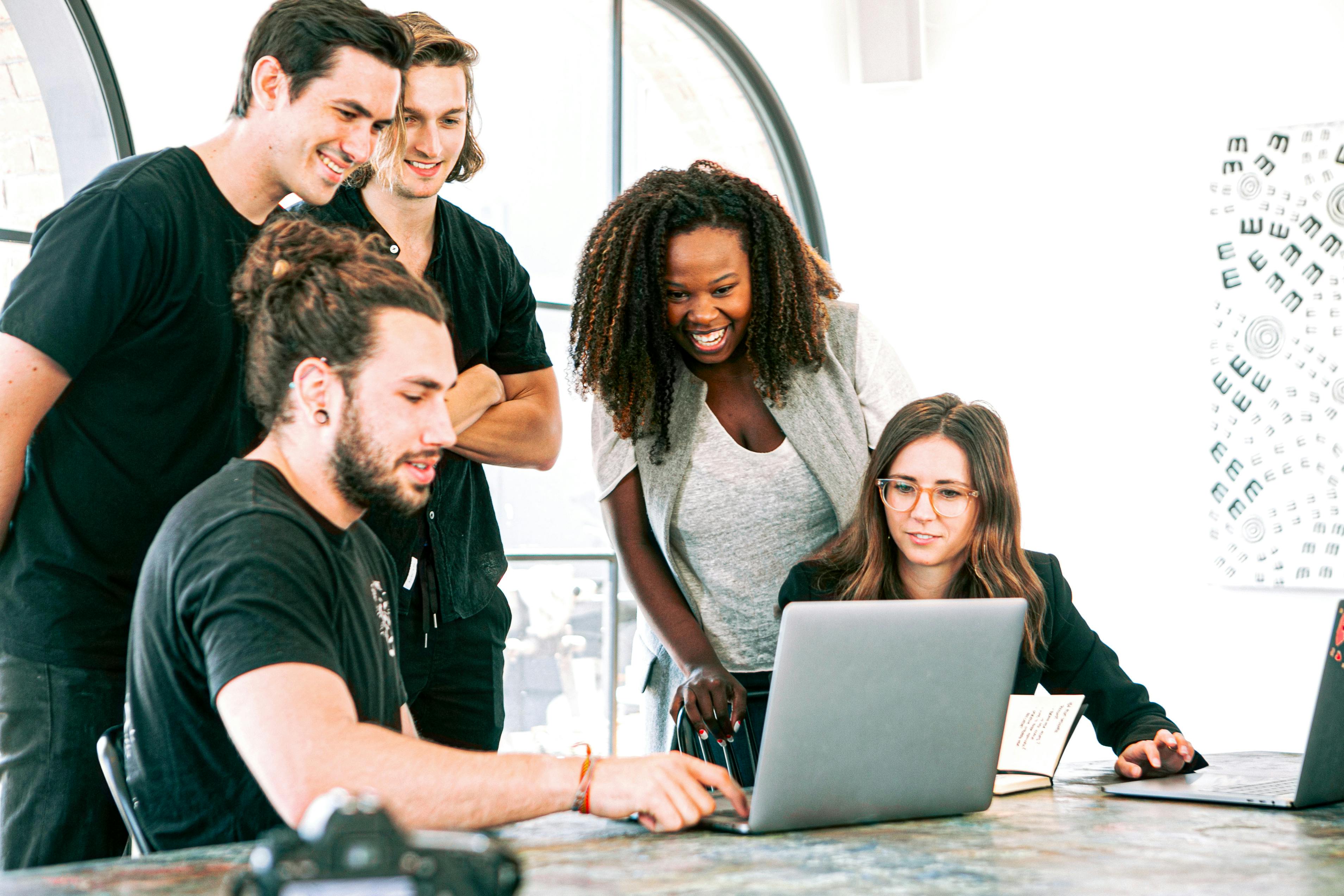 This image shows a group of people looking at a computer in an office.